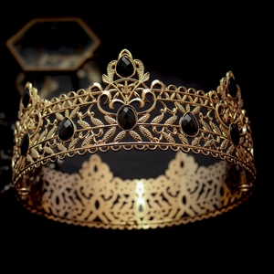 Macro detail of luxury gold crown featuring vintage baroque patterns and black gemstones