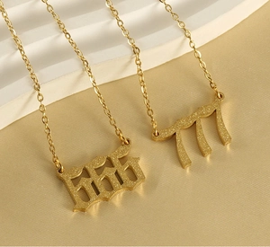 Nahaufnahme der goldenen 555 und 777 Zahlenanhänger mit mattierter Textur und feiner Kette