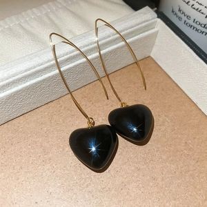 Detailed view of heart-shaped black stone earrings with elegant gold hooks on display