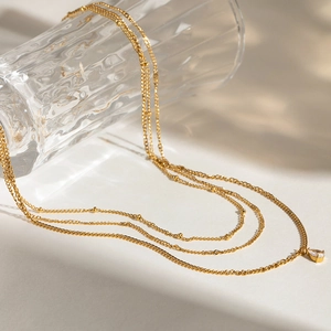 Detailed view of layered gold necklace with teardrop pendant and sparkling white crystals