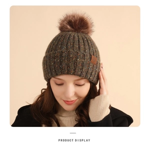 Detailed view of the dark coffee knit beanie with a plush pompom and ear protection