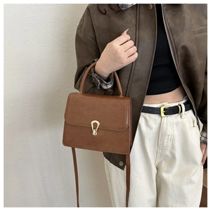 Detail of vintage brown shoulder bag showing golden clasp and smooth oil leather texture
