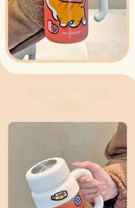 Close-up of a borosilicate glass tea cup with an orange cat print and a sturdy handle