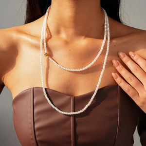 Close-up of double-layer white pearl necklace with golden OT buckle on model