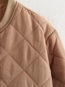 Macro detail of khaki quilted bomber jacket featuring ribbed collar and diamond stitching