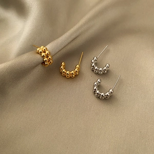 Minimalist U-shaped beaded hoop earrings in gold and silver finish on champagne silk