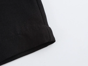 Detailed macro view of the black fabric texture and premium stitched hem on the jumpsuit
