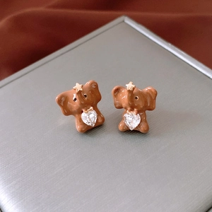 Detail view of brown enamel elephant stud earring with heart-shaped crystal and gold star