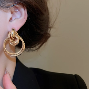 Detailed view of layered gold-tone concentric hoop earrings worn by a model