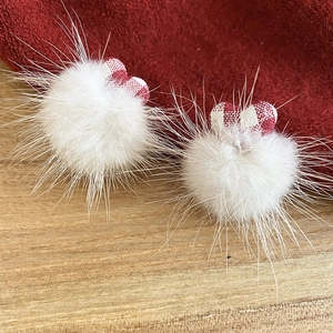 Detailed view of white faux fur pom-pom earrings with delicate red plaid fabric bows