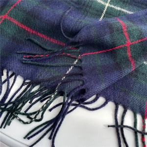 Close-up of classic dark blue and green plaid scarf texture with tassel detail