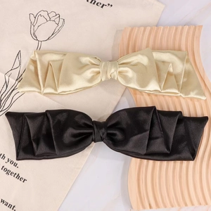 Detail of elegant gold and black satin bow hair clips on a decorative wooden tray