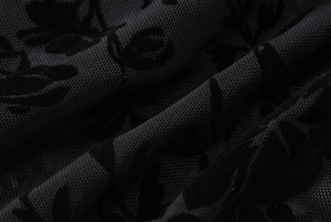 Détails de la texture florale en velours noir sur un tissu en maille transparente