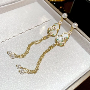 Detailed close-up of gold Hulu earrings with pearls and long tassel fringe details
