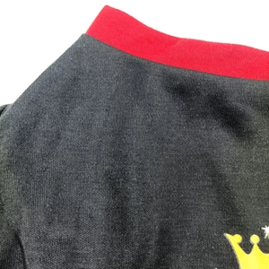 Close-up of black and red stitched pet vest featuring fine knit texture and crown print