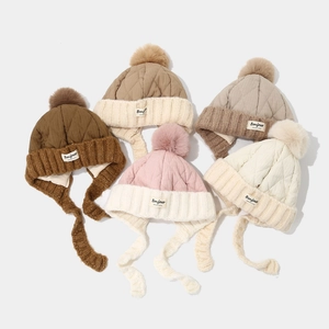 Detailed close-up of winter knit hats with pom poms, ear flaps and Bonjour label detail