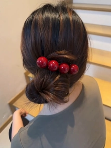 Detail view of large glossy red spherical beads on a stylish spring hair clip hair accessory