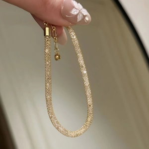 Macro view of gold mesh bracelet filled with crystals and lobster clasp detail