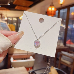 Detail shot of heart-shaped pink stone necklace with halo crystals on a display card