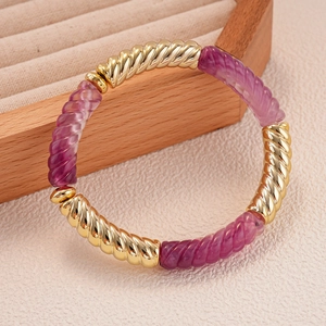 Détail de perles torsadées en acrylique et métal doré sur un bracelet élastique