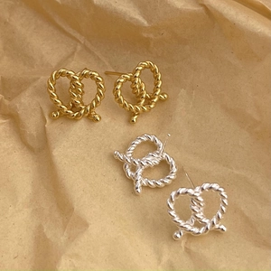 Detail of gold and silver twisted knot pretzel earrings on textured paper