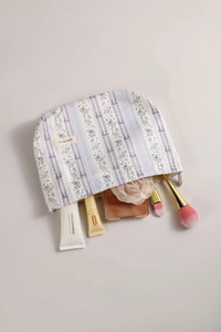 Detailed view of floral striped purple makeup bag with toiletries and brushes