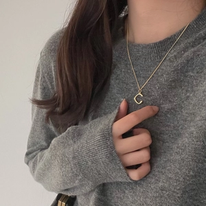 Detail of 925 sterling silver gold necklace with letter C pendant on a model