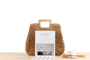 Détail du sac en paille tissé main avec poignée carrée en bois et texture rustique chic