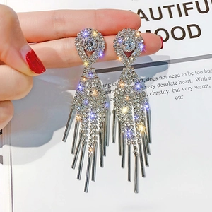 Détail macro de boucles d'oreilles à pompons argentés avec cristaux et chaînettes