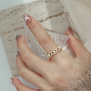 Close-up of a golden double-layered wave ring with white pearls and micro-pave zircons