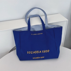 Nahaufnahme der dunkelblauen Canvas-Tasche mit gelber Stickerei und Streifenfutter