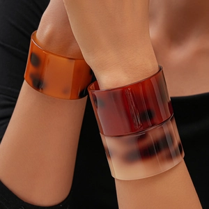 Three wide acetate resin cuff bracelets in amber and tortoiseshell patterns on a model