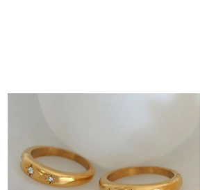 Dettaglio dell'anello a nodo dorato con incisione a stella e piccoli zirconi bianchi