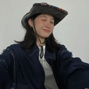 Detail of blue denim bucket hat featuring ethnic woven brim and adjustable chin strap