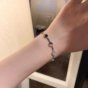 Detail shot of a silver polished snake chain bracelet with round discs on a female wrist