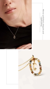 Macro view of gold initial C pendant with multi-color stones and mirror polished finish