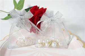 Close-up of grey mesh jewelry pouch with silver glitter bow on a decorative plate