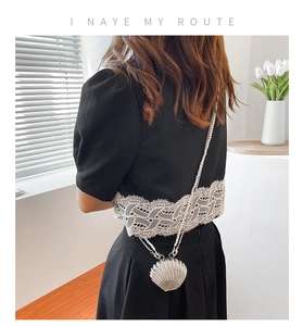 Silver shell clutch bag featuring a white faux pearl chain strap for evening events
