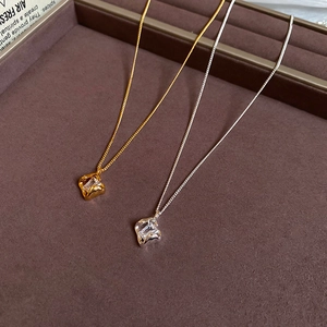 Close-up of 18k gold and silver plated necklaces with square zircon pendants in display box