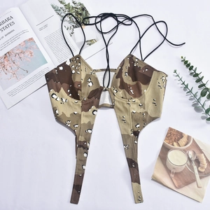 Vue à plat de crop top camouflage avec magazines et plantes sur fond blanc épuré