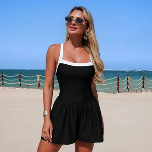 Detail of a black and white contrast one-piece swimdress with pleated skirt outdoors