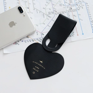 Travel setup with black heart-shaped faux leather luggage tag on a world map with phone
