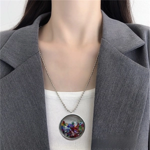 Macro view of a round glass locket pendant filled with vibrant colorful crystal stones