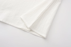 Macro shot of breathable white linen fabric texture with neat stitching on hem detail