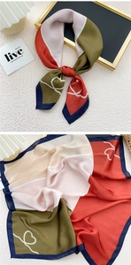 Detailed close-up of a stylish square silk scarf with heart patterns and color blocking