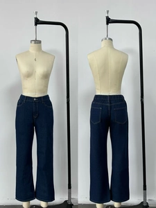 Detail view of high-waisted dark blue denim pants showing front and back pocket design