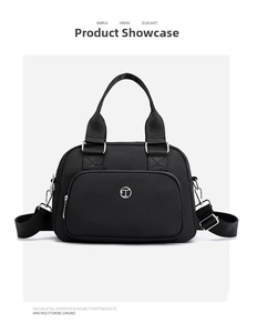 Detail of waterproof black nylon handbag with round metal logo and silver zipper