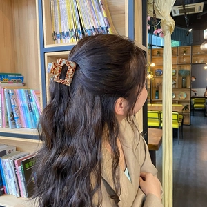 Elegant tortoiseshell acetate hair claw clip worn by a woman in a library setting