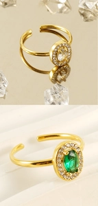 Detail of adjustable 18K gold plated rings featuring oval emerald and clear zircon gems