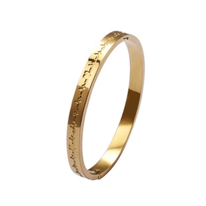 Detail view of a gold clover magnetic bracelet with engraved patterns and side clasp closure